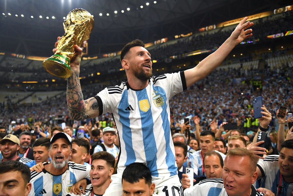 LUSAIL CITY, QATAR - DECEMBER 18: Lionel Messi of Argentina celebrates with the FIFA World Cup Qatar 2022 Winner's Trophy on the shoulders of former teammate Sergio Aguero after the team's victory during the FIFA World Cup Qatar 2022 Final match between A